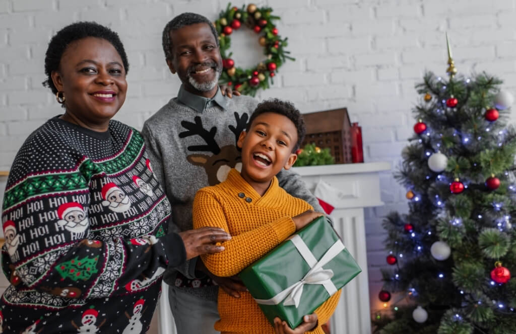 Un petit fils sa mère et son grand père à Noël tenant son cadeau de Noël pour un grand père