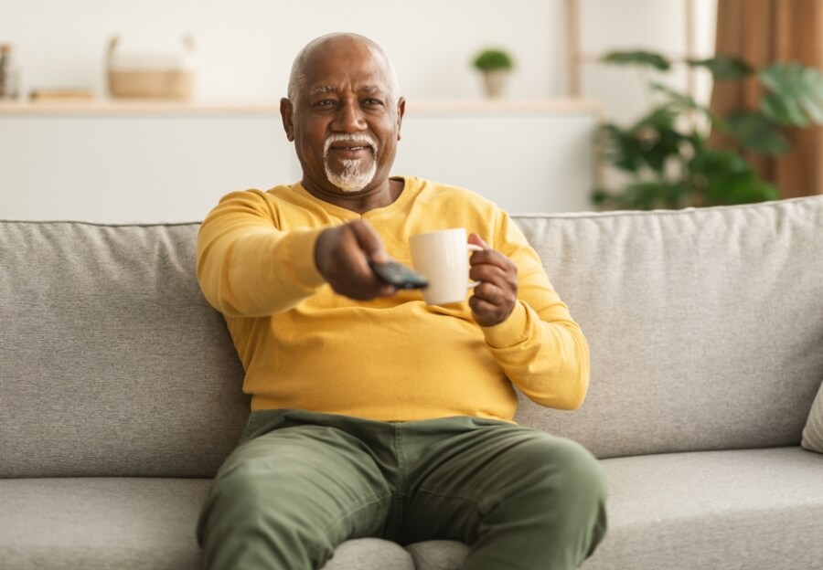 Ein Mann sitzt auf der Sofa und streamt eine Serie